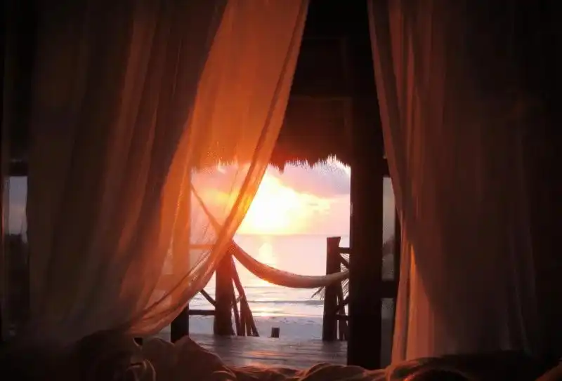 Cortinas abiertas al atardecer, con el mar al fondo.