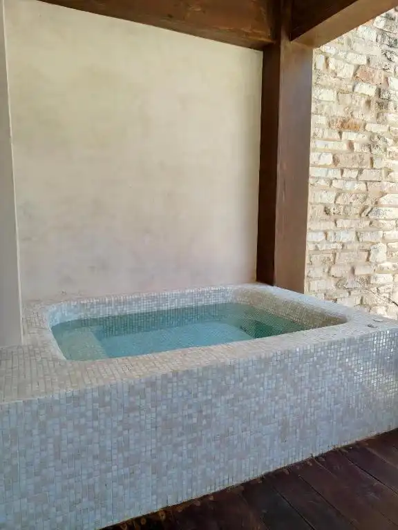 Jacuzzi de mosaico en una terraza de piedra.