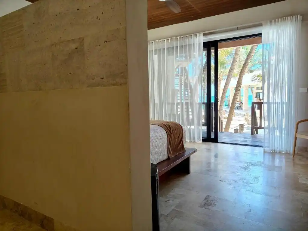 Habitación con el ventanal abierto al balcón y al mar.