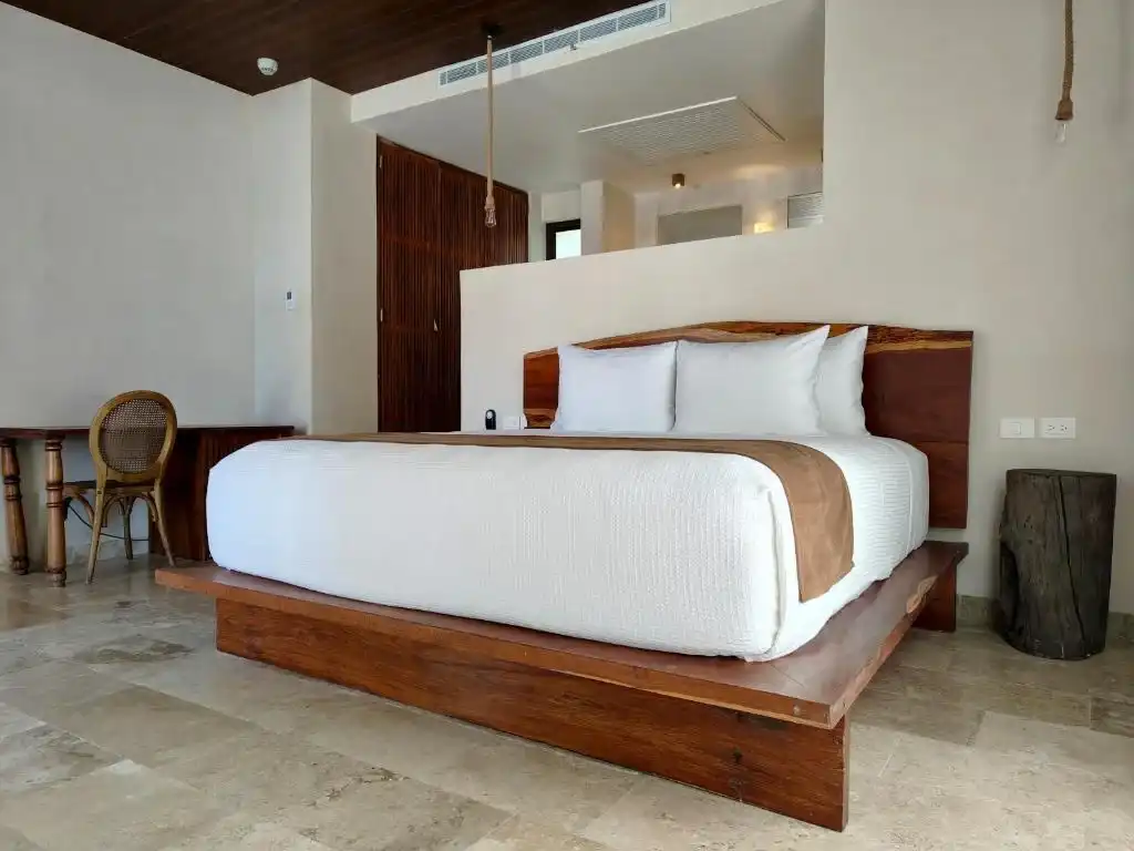 Habitación con cama de madera y un sillón junto a la ventana.