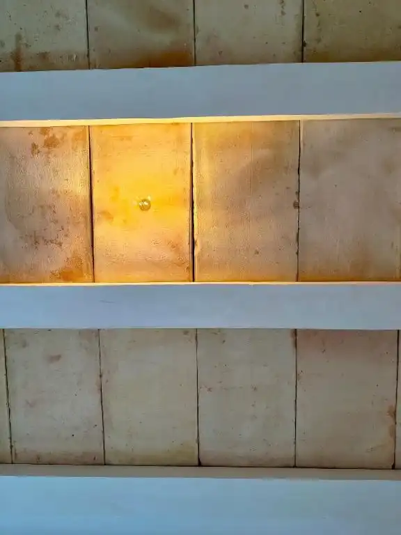 Cabecera de paneles de madera, iluminada desde abajo.