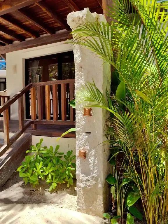 Escalera exterior con una columna de piedra y vegetación.
