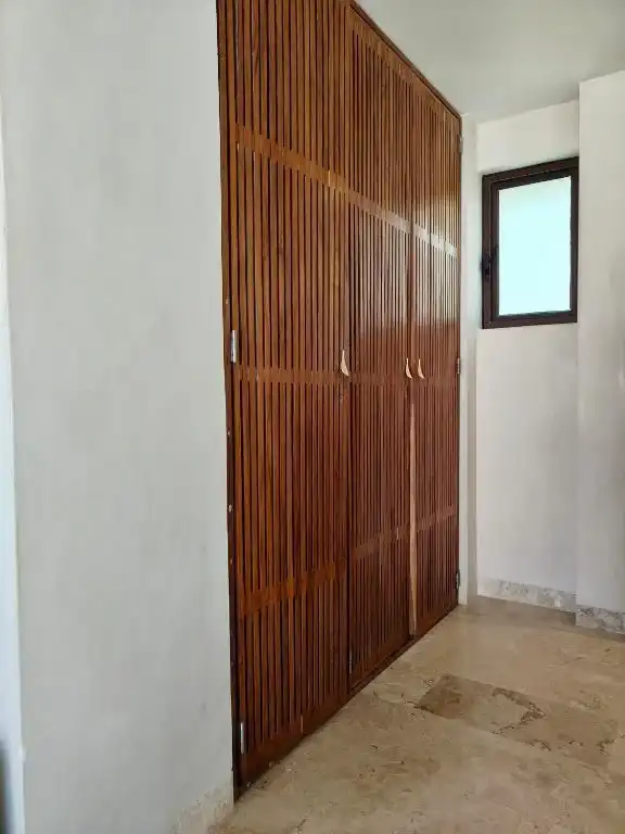 Clóset de puertas de madera, junto a una ventana.
