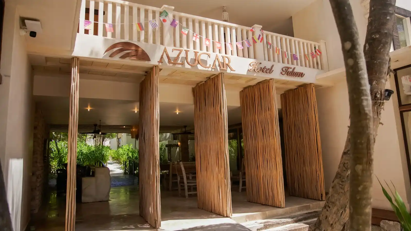 Fachada del hotel con su rótulo, los banderines de papel picado y las columnas de madera.