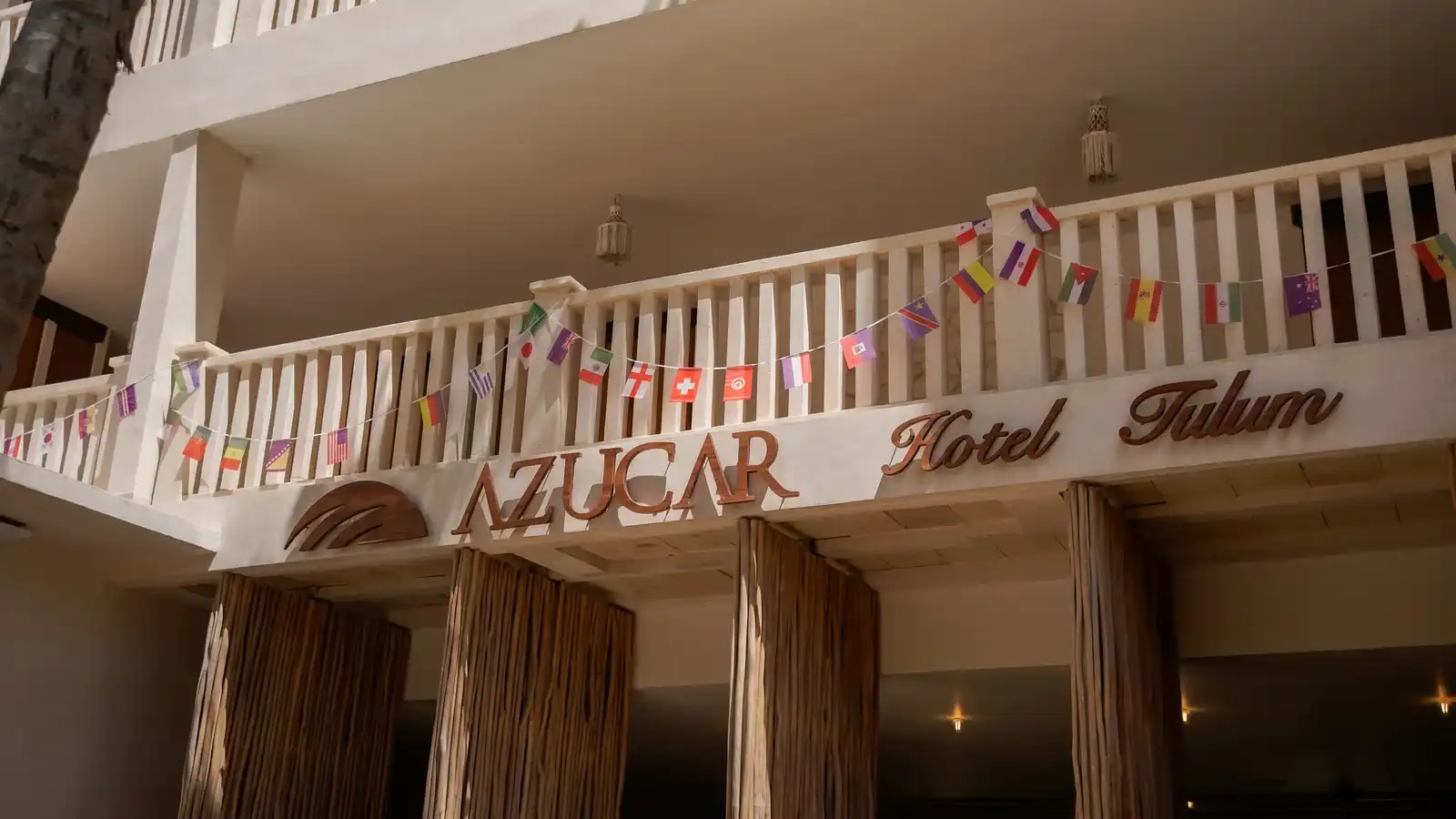 La fachada del hotel con el rótulo «Azucar Hotel Tulum» sobre las columnas.