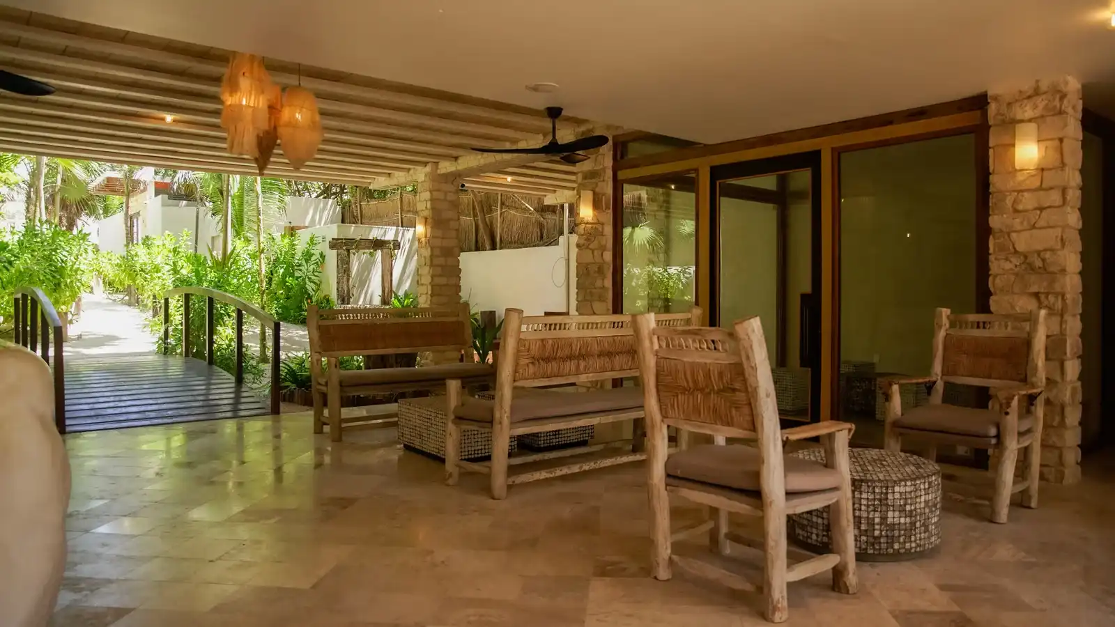 Estar abierto con bancas y butacas de madera, junto al andador del jardín.