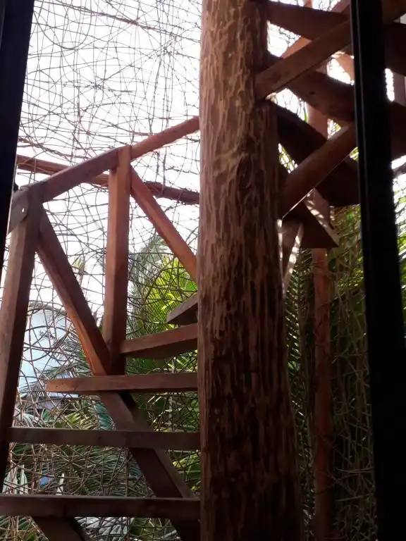 Barandal de madera y troncos, con la vegetación del jardín detrás.