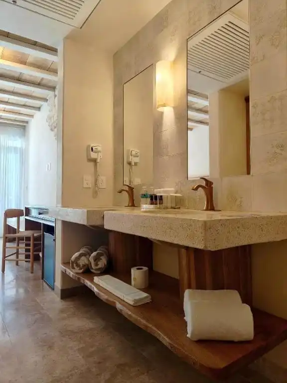 Lavabo de piedra con espejo y una repisa de madera.