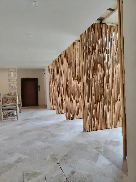 Pasillo interior con paneles de bambú y una puerta de madera.