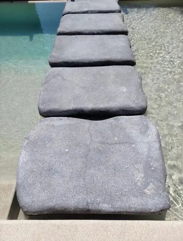 Pasaderas de piedra dentro del agua de la alberca.