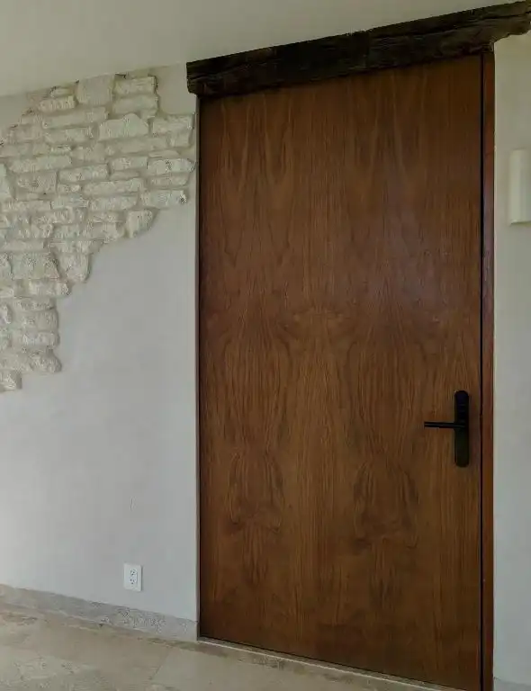 Puerta de madera de la habitación, junto a un muro de piedra.